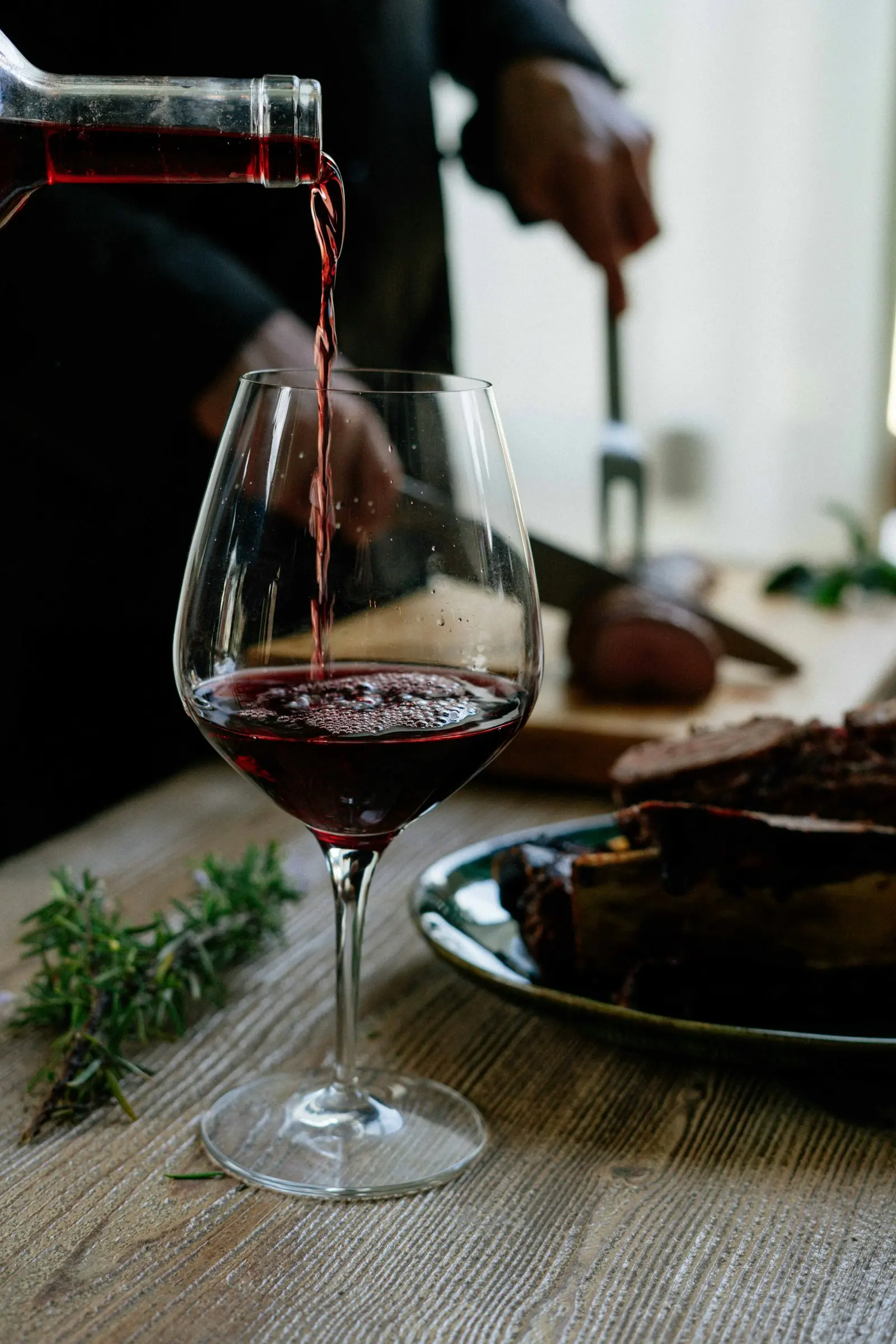 Red wine being poured into a glass in the low light of the cellar